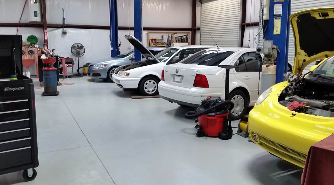 The Wolfsburg Tech service bay, with a Jetta, a Passat and a New Beetle up on lifts.